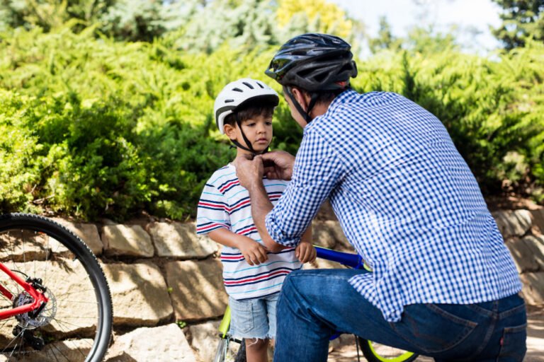 Padre ayudando a hijo a usar casco de bicicleta