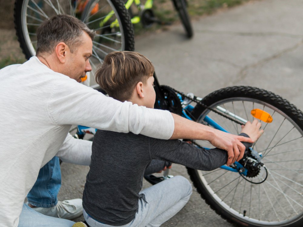 Padre enseñando a su hijo arreglando la bicicleta